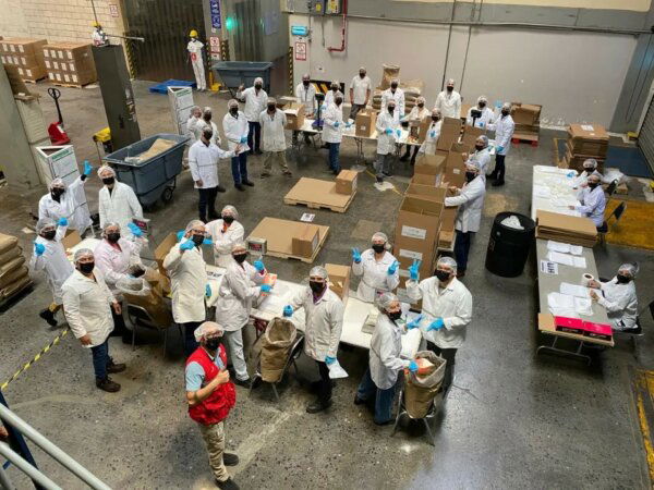 Group of factory employees packing porridge and waving
