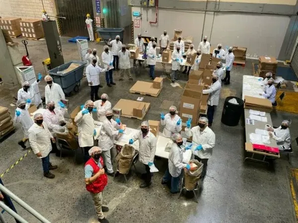 Group of factory employees packing porridge and waving